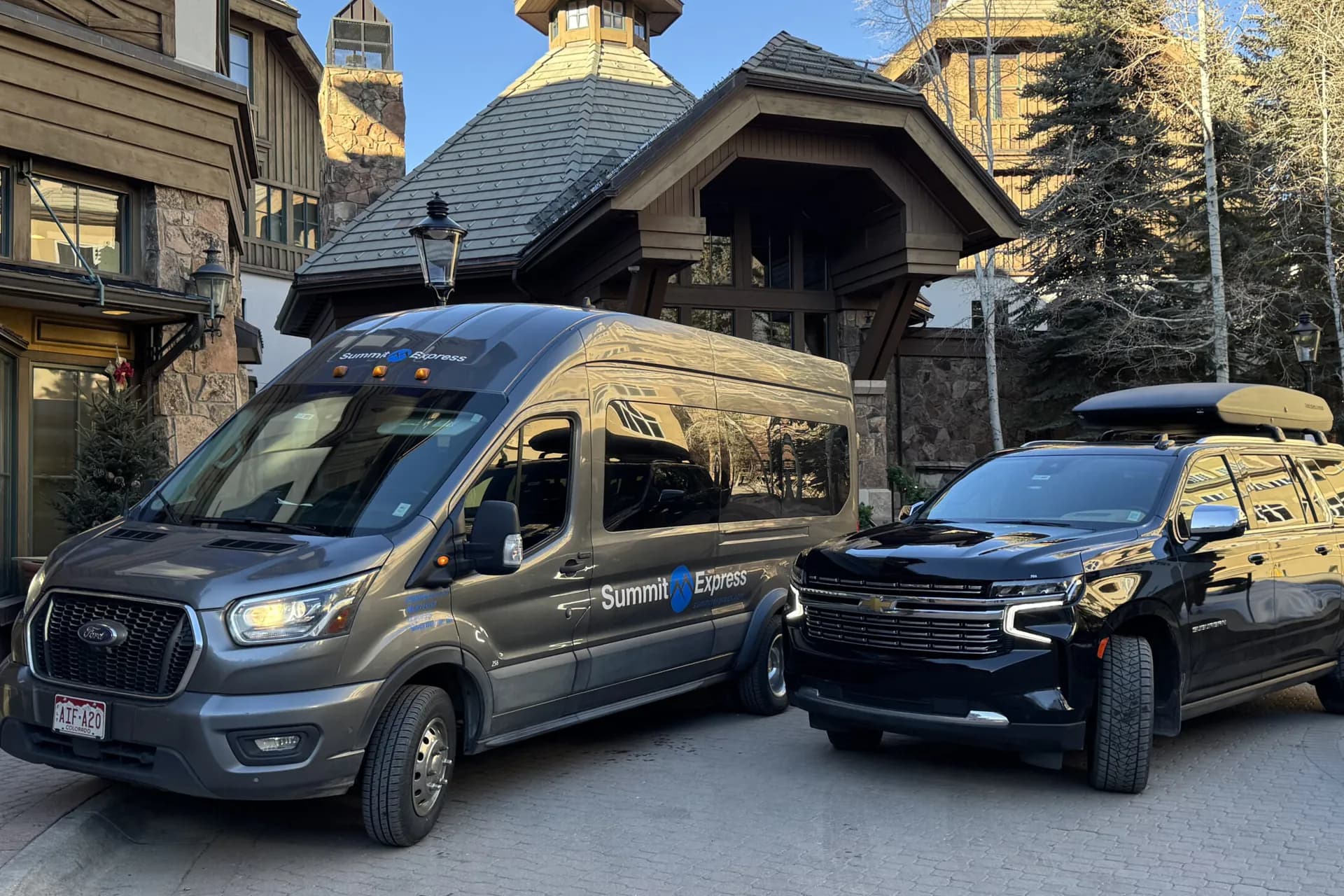 Summit Express van and SUV in front of a mountain lodge